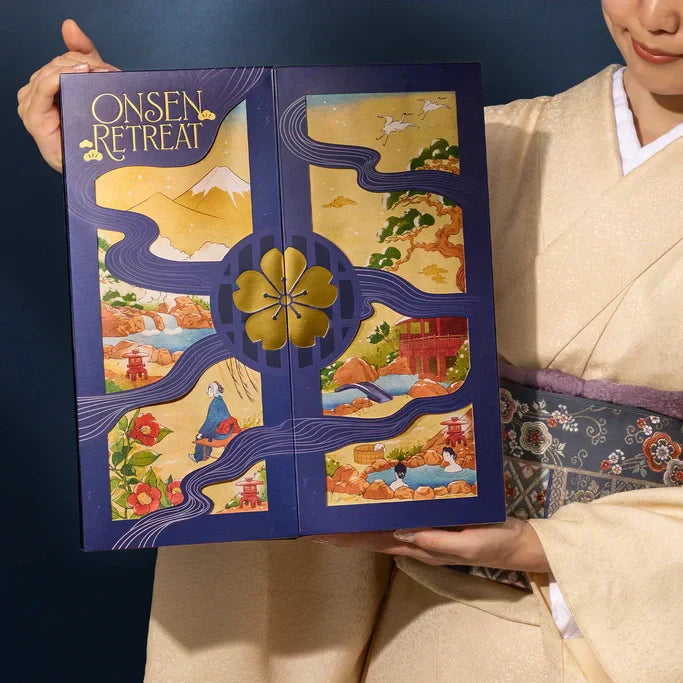 A woman in a beige kimono holding the Onsen Retreat Advent Calendar. 